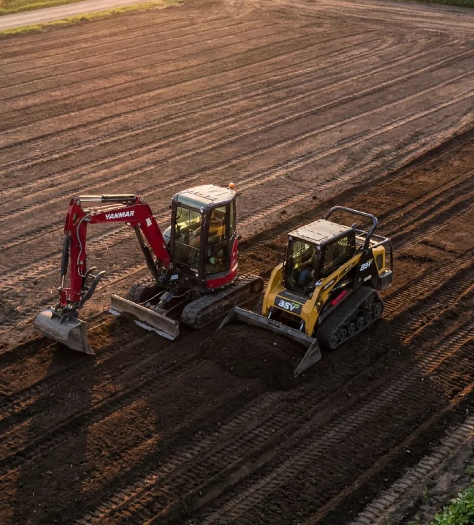 Mini excavator and tracked loader preparing a level agricultural site